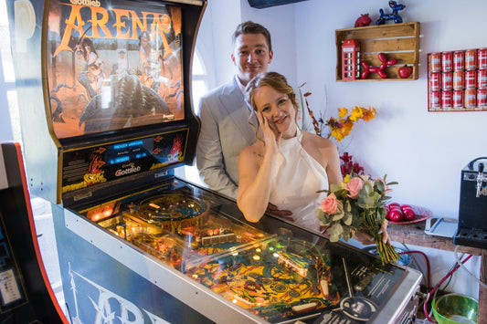 Valère and Haley of Pinballs Store beside a Gottlieb Arena pinball machine